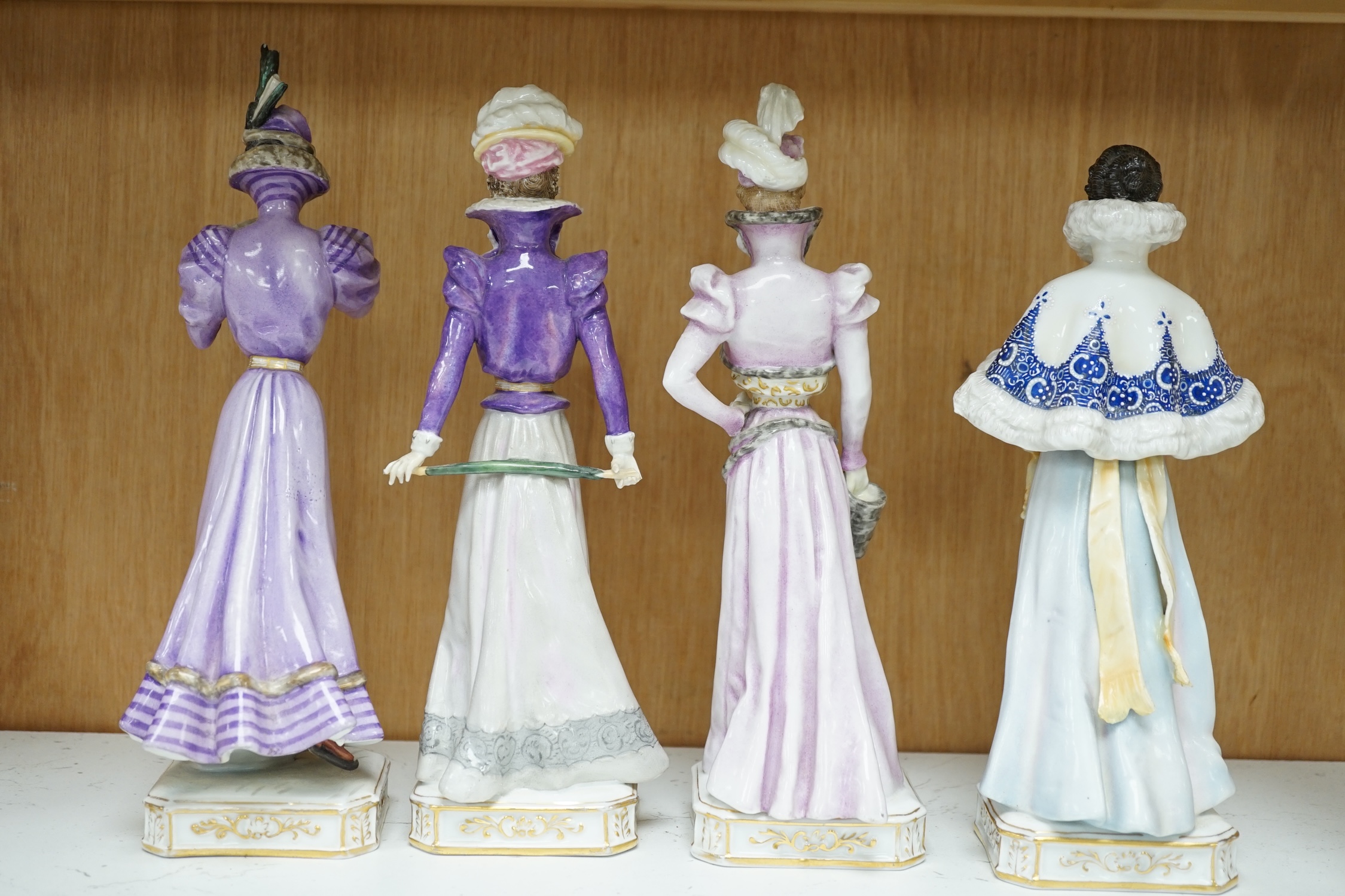 Four German Plaue porcelain figures of Edwardian fashionable ladies, tallest 27.5cm high. Condition - poor some chips